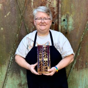 Julia Mann holding finished pot, pierced lantern, glazed in mamo and plum chun