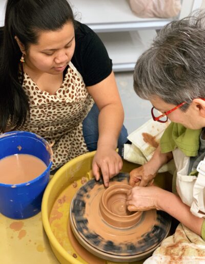 Katie Meili Messersmith teaching a student throwing on the potters wheel, TVP Teaching Center class