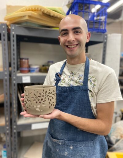 Teaching Center student smiling while holding their leather hard pot that has been pierced, intermediate wheel class