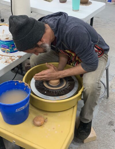 Teaching center student male centering throwing at potters wheel, beginning wheel class