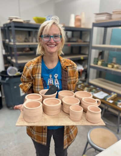Teaching Center student smiling while holding their bisqueware, beginning wheel class